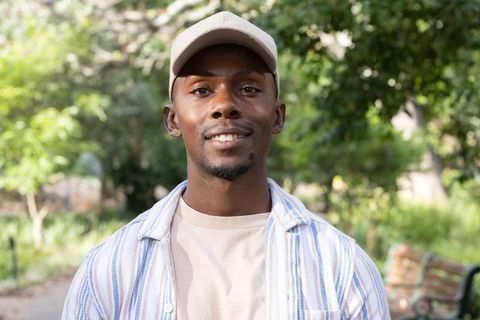 African american man wearing baseball cap smiling in sunlit park casual lifestyle portrait
