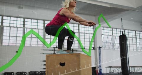 Woman Performing Box Jumps with Fitness Data Interface in Gym