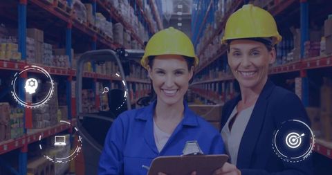 Women supervising warehouse operations wearing hard hats and checking inventory