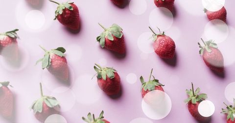 strawberries scattered on pink background with light spots - Download Free Stock Images Pikwizard.com