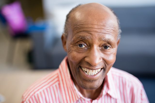This image captures a joyful senior man with a receding hairline smiling warmly at a nursing home. Ideal for use in healthcare, retirement, and elder care promotions, as well as articles on aging, happiness, and senior living.