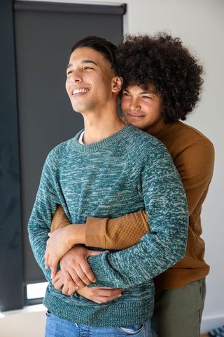 Diverse male couple sharing affectionate embrace in cozy home