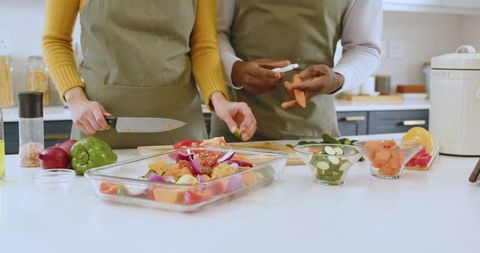 Diverse Couple Slicing Vegetables for Healthy Cooking in Modern Kitchen