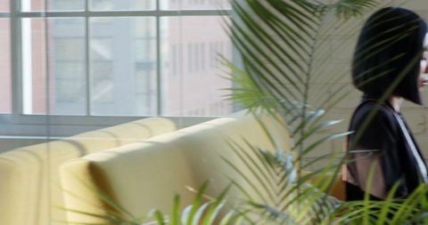 Side Profile of Woman in Modern Office with Plants and Yellow Seating