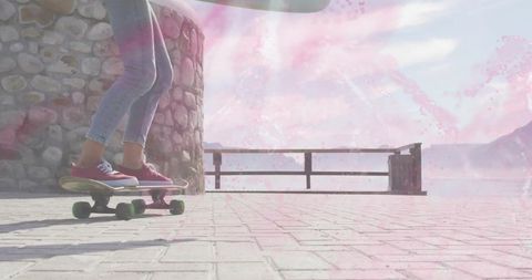 Balancing on longboard at sunlit waterfront promenade with red sneakers and green wheels