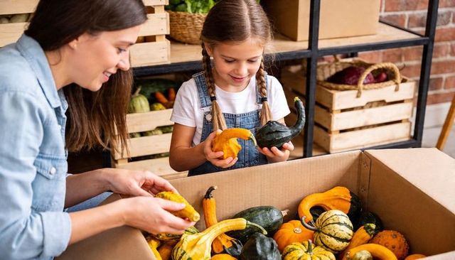 Mother and daughter selecting colorful gourds at rustic farmers market