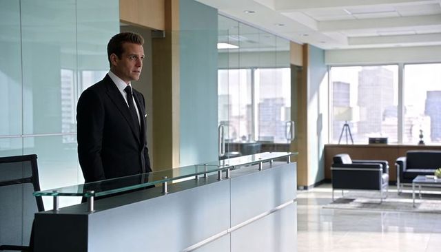 Executive standing behind glass reception desk in sleek modern corporate office city view