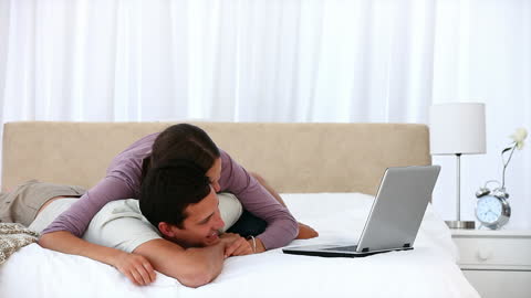 Couple Enjoying Time Together with Laptop on Bed