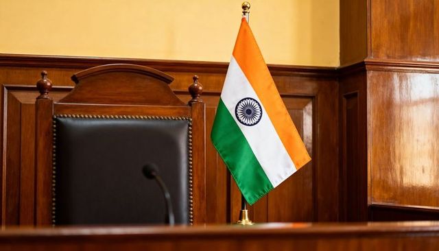 Indian tabletop flag on gold stand beside judge bench with microphone in courtroom