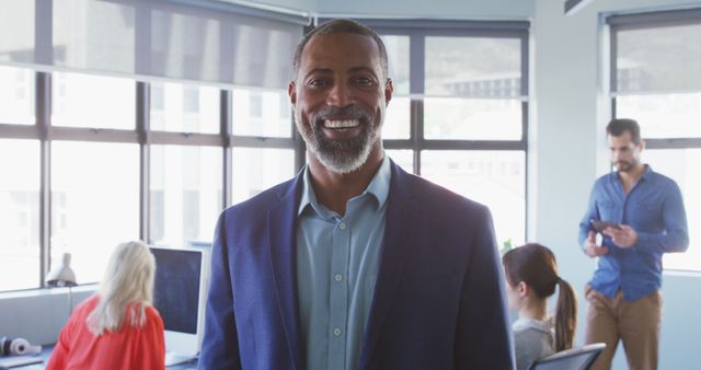 Smiling Businessman in Modern Office with Colleagues Working - Download Free Stock Images Pikwizard.com