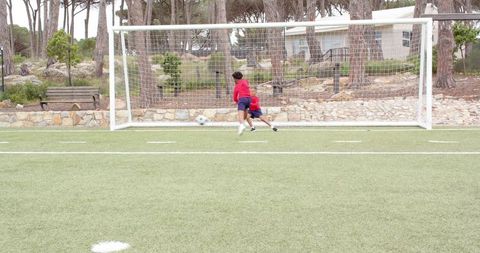 Youth Soccer Players Kicking Ball on Grassy Field Near Goal