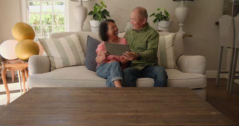 Senior Couple Video Chatting on Tablet from Cozy Living Room