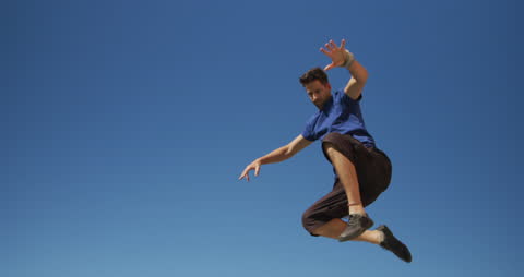 Man Performing Parkour Jump on Sunny Rooftop in Casual Attire