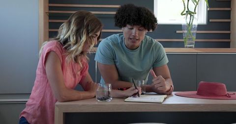 Young couple enjoying drinks and discussing in bright kitchen