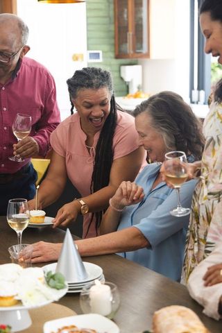 Multigenerational friends celebrating in kitchen sharing cupcake and wine, joyful moment