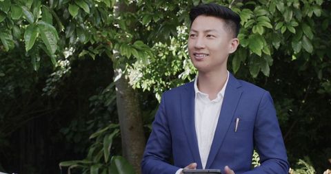 Groom holding smartphone in garden ceremony