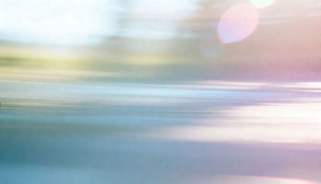 Pastel seascape flowing with motion blur, soft lens flare and reflective horizon glow