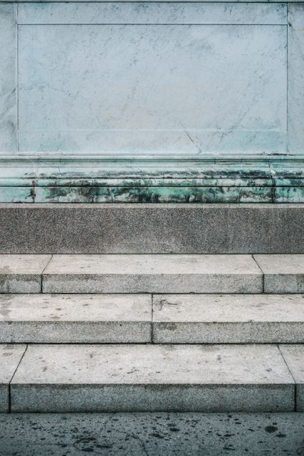 Marble steps made of stone lead to an aged, historical building. Ideal for use in historical contexts, architecture studies, urban exploration themes, or content related to classical structures and monuments.