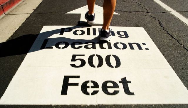 Pointing arrow leading to polling location 500 feet with pedestrian walking on street