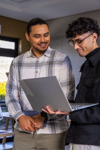 Two colleagues collaborating over laptop in modern office meeting room, daylight teamwork