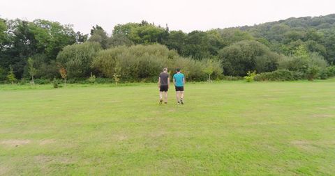 Two Men Jogging in Lush Green Park Promoting Fitness