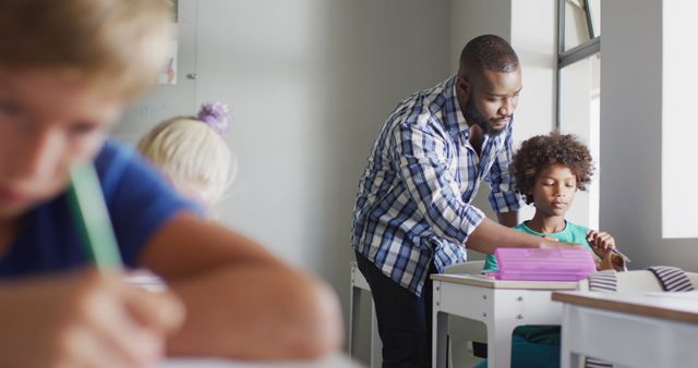 Image of happy african american male teacher helping biracial boy during lessons - Download Free Stock Photos Pikwizard.com