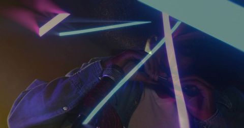 Playing harmonica under neon tubes with denim jacket and microphone, moody lighting