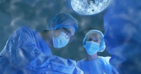 Surgical team performing operation in sterile operating room wearing blue gowns and masks