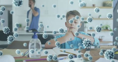 Young boy studying with virus overlay and sanitizer on table