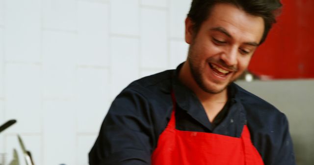 Smiling Male Chef Wearing Red Apron Preparing Food in Kitchen - Download Free Stock Images Pikwizard.com