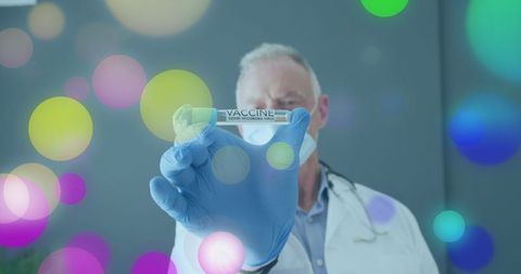 Senior Doctor Displaying COVID-19 Vaccine Amidst Colorful Lights