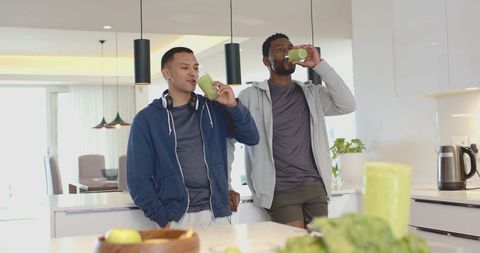 Diverse friends drinking green smoothies at modern kitchen island for healthy lifestyle