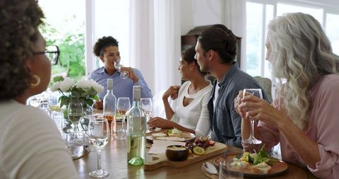 Friends Enjoying Lively Meal and Conversation Around Dining Table