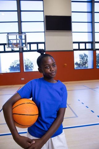 Confident Young Athlete Holding Basketball in Gymnasium
