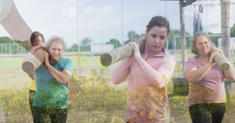 Women carrying logs displaying teamwork and strength in outdoor fitness