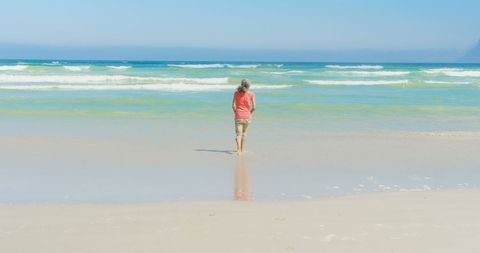 Senior Woman Enjoying Beach Walk on Sunny Day - Download Free Stock Images Pikwizard.com