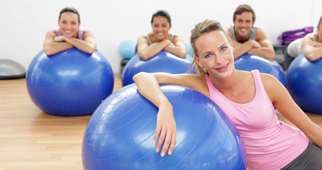 People smiling during a pilates class with stability balls, indicating a positive, inviting atmosphere. Useful for content related to fitness, group exercises, healthy lifestyles, gym advertising, and workout tutorials.
