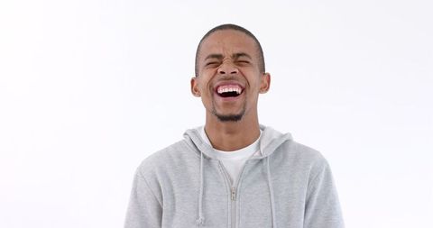 Young Man Laughing Joyfully in Casual Gray Hoodie