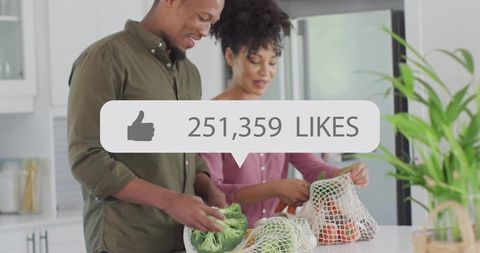Young couple packing fresh vegetables into reusable mesh bags at bright modern kitchen