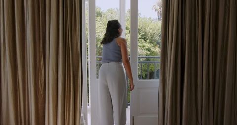 Woman enjoying fresh air on balcony with open doors