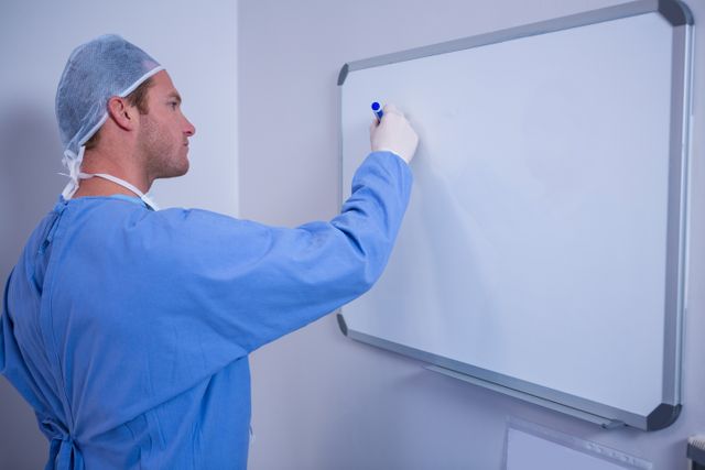 Male surgeon writing on whiteboard in hospital