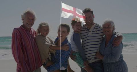 Smiling family holding flag at ocean shoreline celebrating togetherness