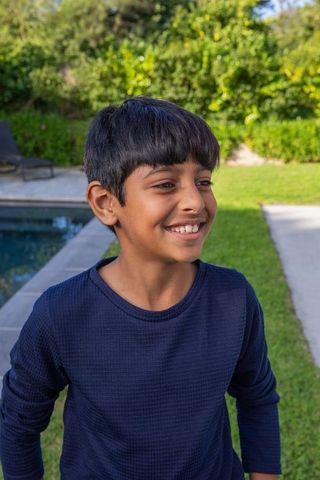 Asian Boy Smiling in Backyard Near Pool on Sunny Day