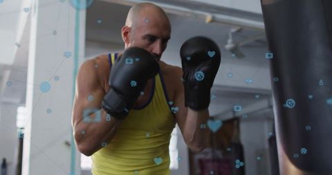 Muscular boxer training with blue health-tech overlay hitting heavy bag in industrial gym