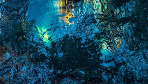 Iridescent rippling water surface with neon circular ripples and glassy reflections