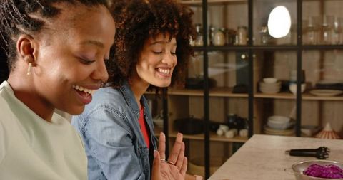 Diverse women chatting and laughing at modern kitchen counter during casual home gathering