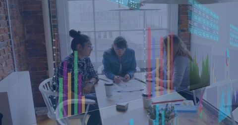 Women collaborating while reviewing analytics and charts in bright modern urban office