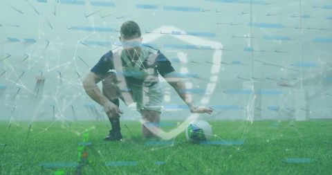 Kneeling soccer player holding ball on turf with augmented cyber shield network overlay