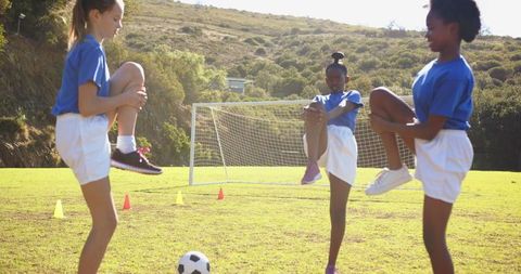 Young girls warming up on soccer field with vivid sunshine
