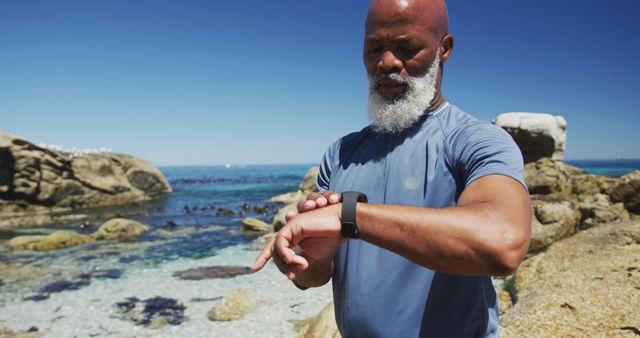 Senior African American Man Using Smartwatch on Beach - Download Free Stock Images Pikwizard.com